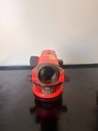 Red SECO automatic level from the front, showing the objective lens, leveling base and focus knobs on a black tray