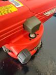 Red surveying level close-up showing the circular bubble vial, focus knob, model label and calibration sticker
