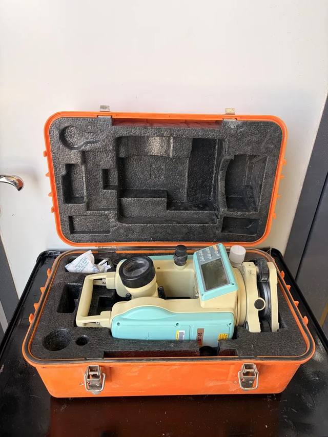 Leica LDT-05 theodolite in its open orange hard case, with the lid foam and silica gel packet visible