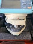Digital theodolite keypad and screen above the tribrach base with leveling screws, sitting in a foam case
