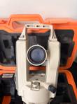 Nikon NE-20S theodolite from the front, showing the telescope lens and carrying handle in its orange case