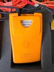 Back of an orange Fluke unit in foam with a Made in USA label and cords above it