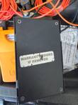 Black module with a worn Warranty Voided If Removed label, beside an orange Fluke unit and patchcord report