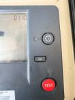 Power, Ω/I and red TEST buttons beside the tester's LCD