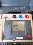 Tester display and black, blue and red terminals with a calibration sticker