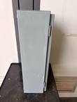 Side of the gray steel enclosure showing hinges and a round knockout