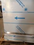 Lower front corner of Follett refrigerator with protective film, blue arrow and vent grille