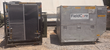 Black-framed chiller with mesh screens beside the aluminum FieldCore chiller enclosure on gravel