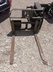Pallet forks with two long tines and a steel backrest frame with an MW logo cutout, quick-attach carriage