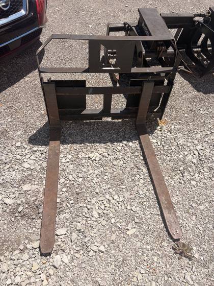 Pallet forks with two long tines and a steel backrest frame with an MW logo cutout, quick-attach carriage