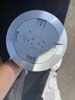 Round brushed-aluminum poke-thru floor outlet cover with gray plastic inserts, top view
