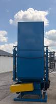 Rear of the tall blue shot blast cabinet on its steel skid base, yellow guard and control box