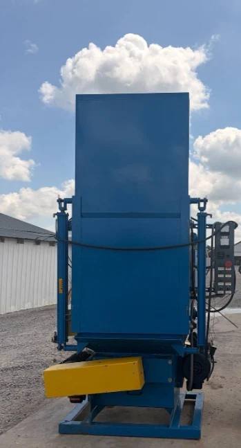Rear of the tall blue shot blast cabinet on its steel skid base, yellow guard and control box