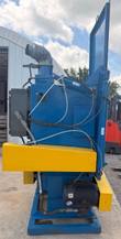 Blue shot blast cabinet side view with dust collector duct, yellow guards and drive motor
