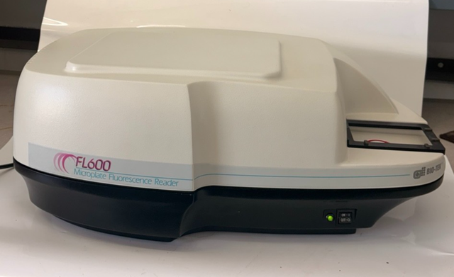 BioTek FL600 microplate fluorescence reader, cream cover on black base, plate carrier at right