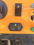 Hour meter, black fan switch and green button on the orange crusher control panel