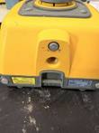 Base of the yellow LL100N laser level showing the threaded tripod mount, laser warning label and data plate