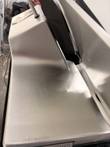 Brushed stainless base surface of the Bizerba slicer with light scratches and a warning label corner