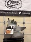 Bizerba SE 12 D US meat slicer on a black cart, product holder raised, red and yellow danger label on the side