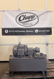 Industrial hydraulic power unit with Delco motor and gray steel reservoir, shown in front of a Chupp Surplus banner