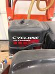 Cyclone air cleaner housing on the floor saw engine, with orange frame and braided water hose behind