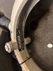 Rotary peeler ring close-up with tension spring and grey roller wheels, light rust on the silver segments